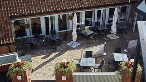 An outdoor patio with tables and chairs, a covered seating area, and flower boxes.
