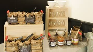 Un área de cocina con recipientes etiquetados para frutas, especias y salsas, además de vasos y frascos en estanterías.