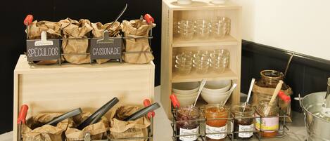 A kitchen area with labeled containers for fruits, spices, and sauces, along with glassware and jars on shelves.
