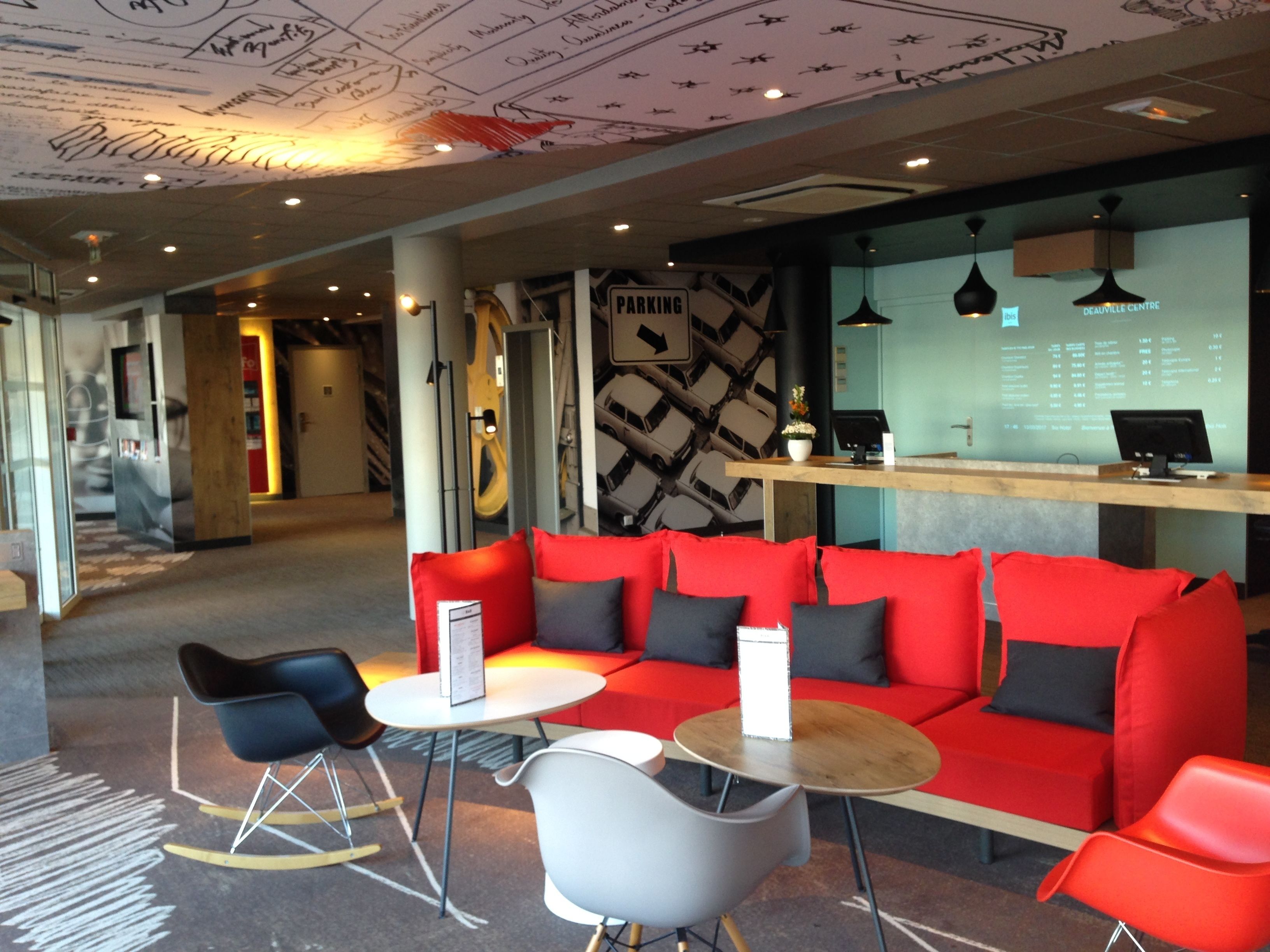 A modern interior with a red sofa, black and grey chairs, and a wooden table.