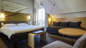 Une chambre d’hôtel moderne dotée d’un grand lit, d’un canapé, d’une petite table ronde et d’un plafond au design original et à la texture particulière.