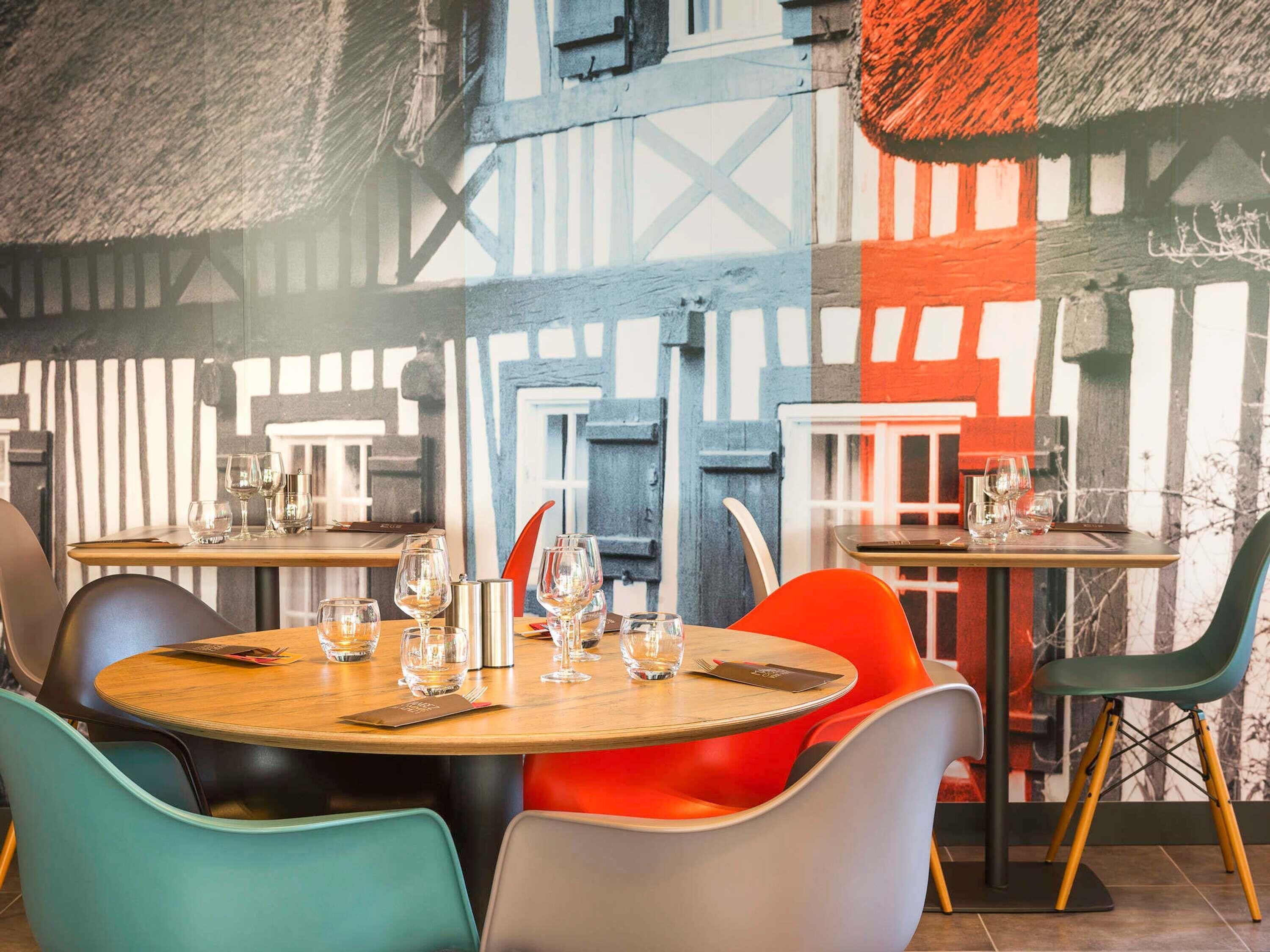 A restaurant interior with round tables, chairs, and a mural on the wall.