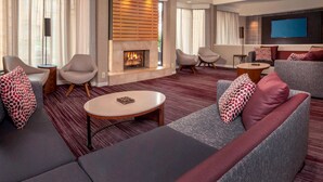 A modern living room with a fireplace, sofas, armchairs, and a flat-screen TV. - Sonesta Select Newark Christiana Mall (Newark)
