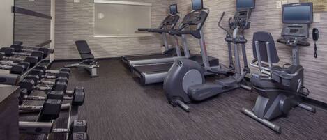 A fitness center with treadmills, elliptical machines, and dumbbells.