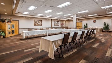 A conference room with long tables, chairs, and a wooden cabinet with glass doors.