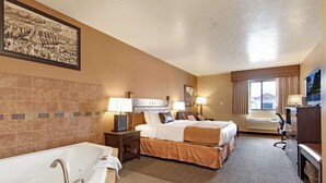 Ein Hotelzimmer mit einer großen Badewanne, zwei Betten, einem Schreibtisch und einem Fernseher.