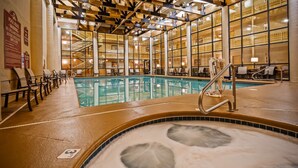 Ein Hallenbad mit klarem Wasser, eine Whirlpool-Anlage und Liegestühle.