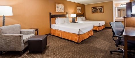 Een hotelkamer met twee bedden, een bureau, een stoel, een lamp en twee aan de muur bevestigde schilderijen.