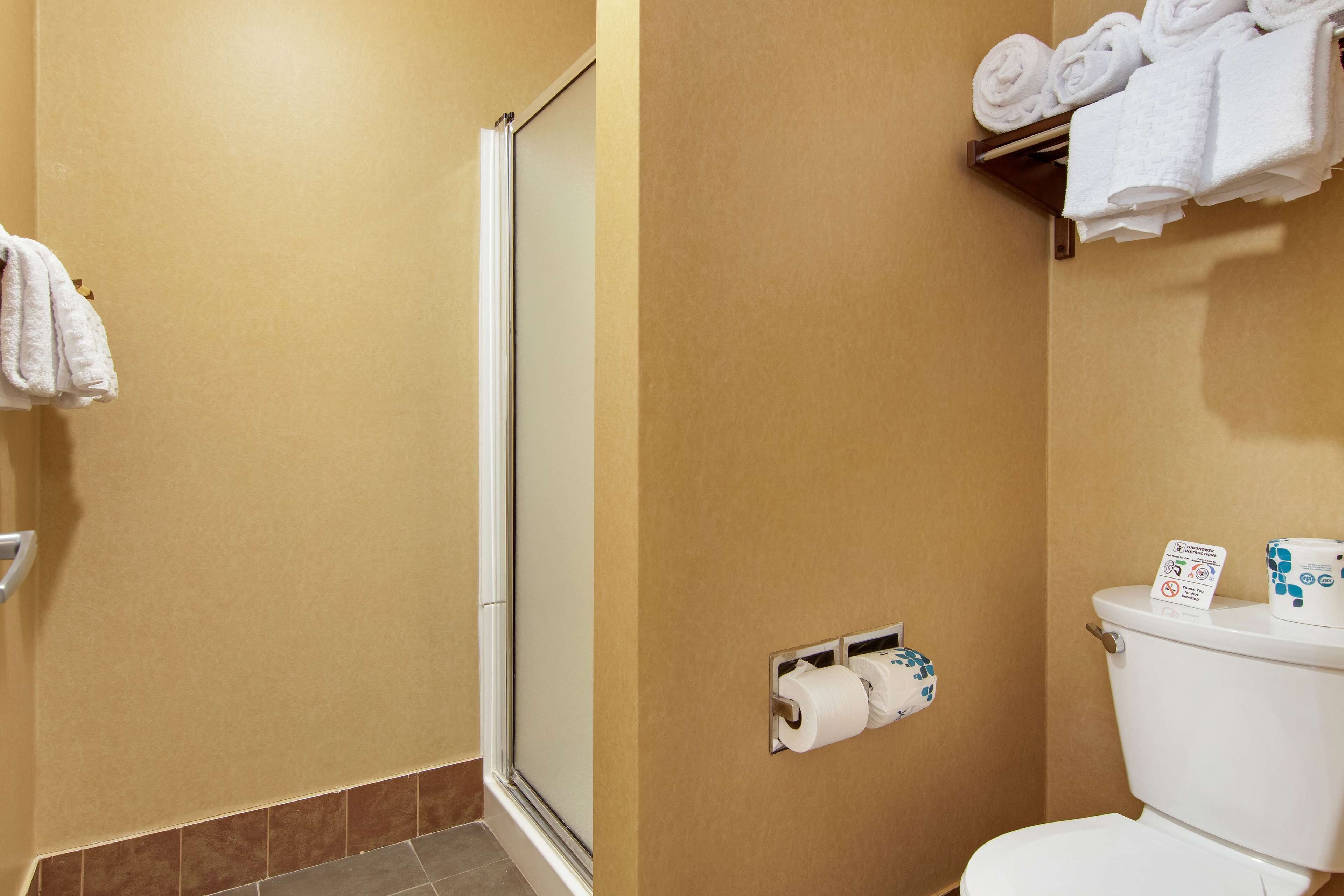 Un baño con inodoro, toallero y toallas, y dispensador de papel higiénico.