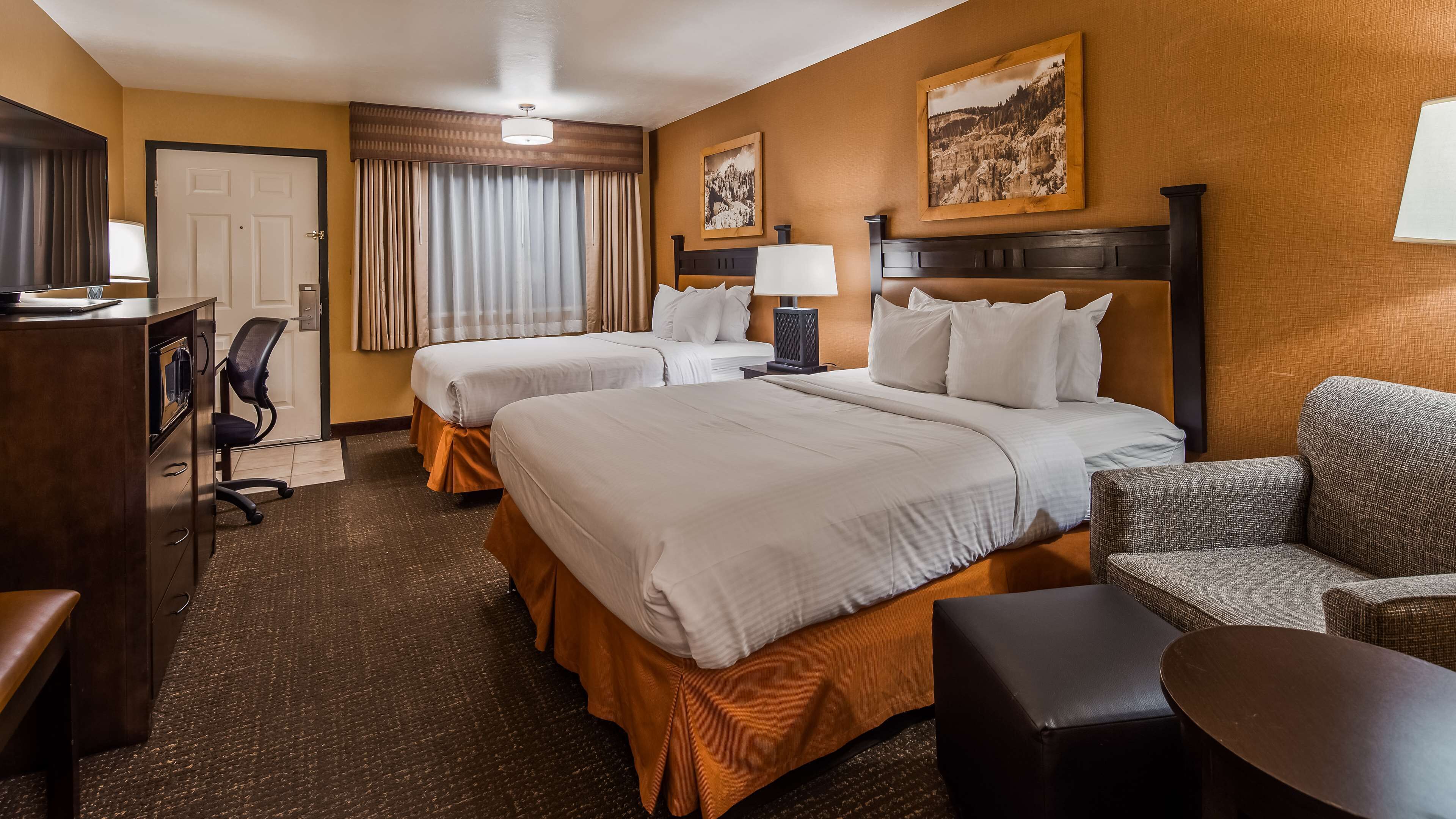 Une chambre d’hôtel avec deux lits, un bureau, une chaise et une petite table.