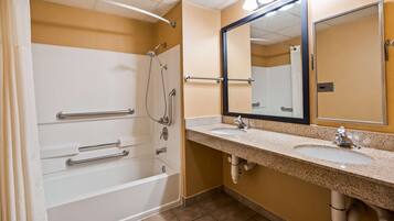 A bathroom with a shower, grab bars, a sink, and a mirror.