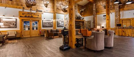 A rustic interior with wooden walls, mounted animal heads, and a reception desk advertising airplane and helicopter flights.
