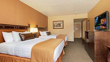 A hotel room with two beds, a TV, a desk, and a framed picture on the wall.