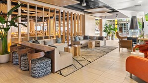A modern lounge area with a wooden partition, seating arrangements, and a large potted plant.