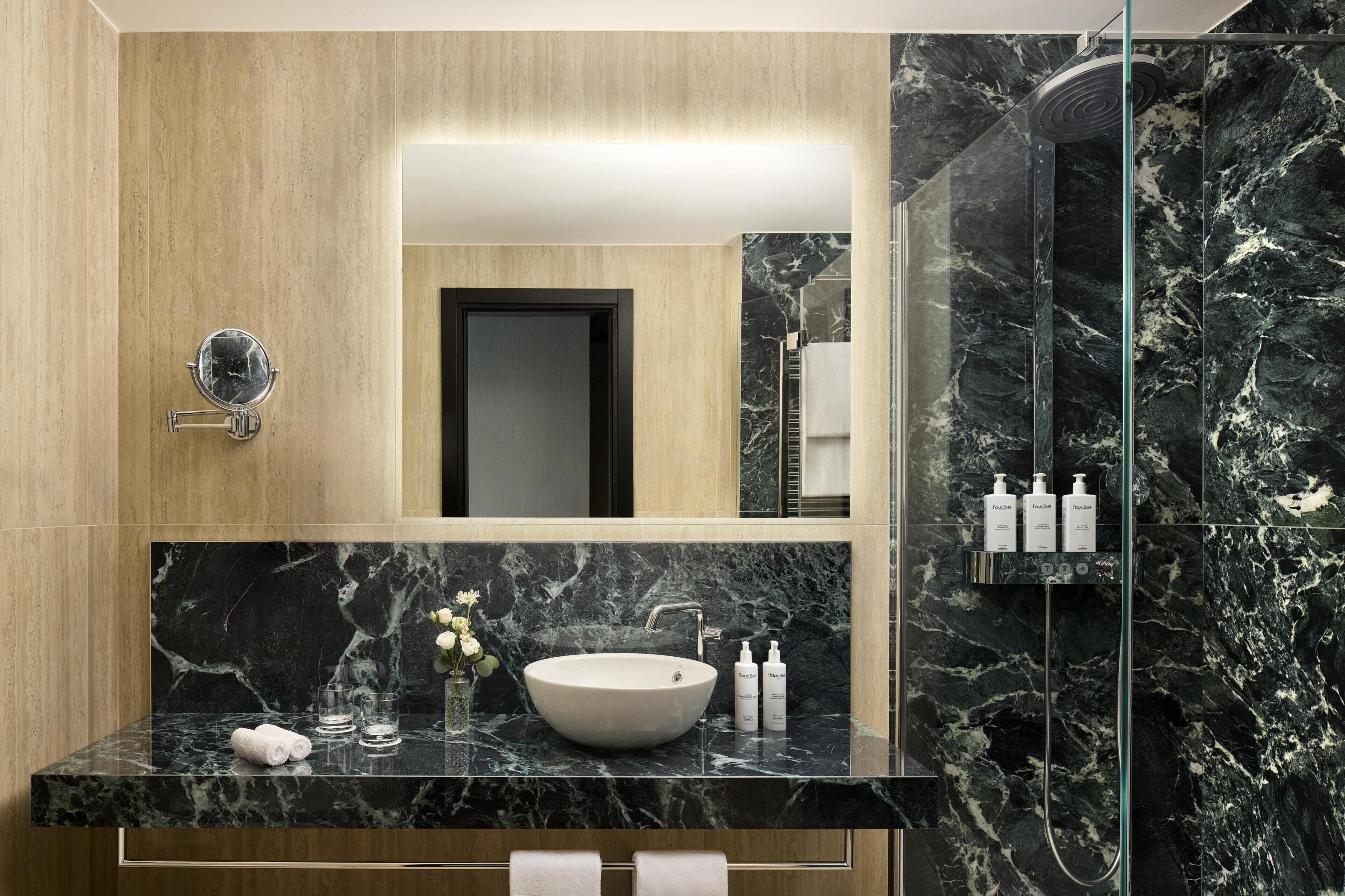 Un baño moderno con tocador de mármol, un espejo grande y cabina de ducha de vidrio.