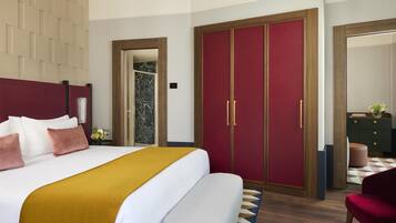 Habitación de hotel con una cama grande, armario, espejo y zona de estar.