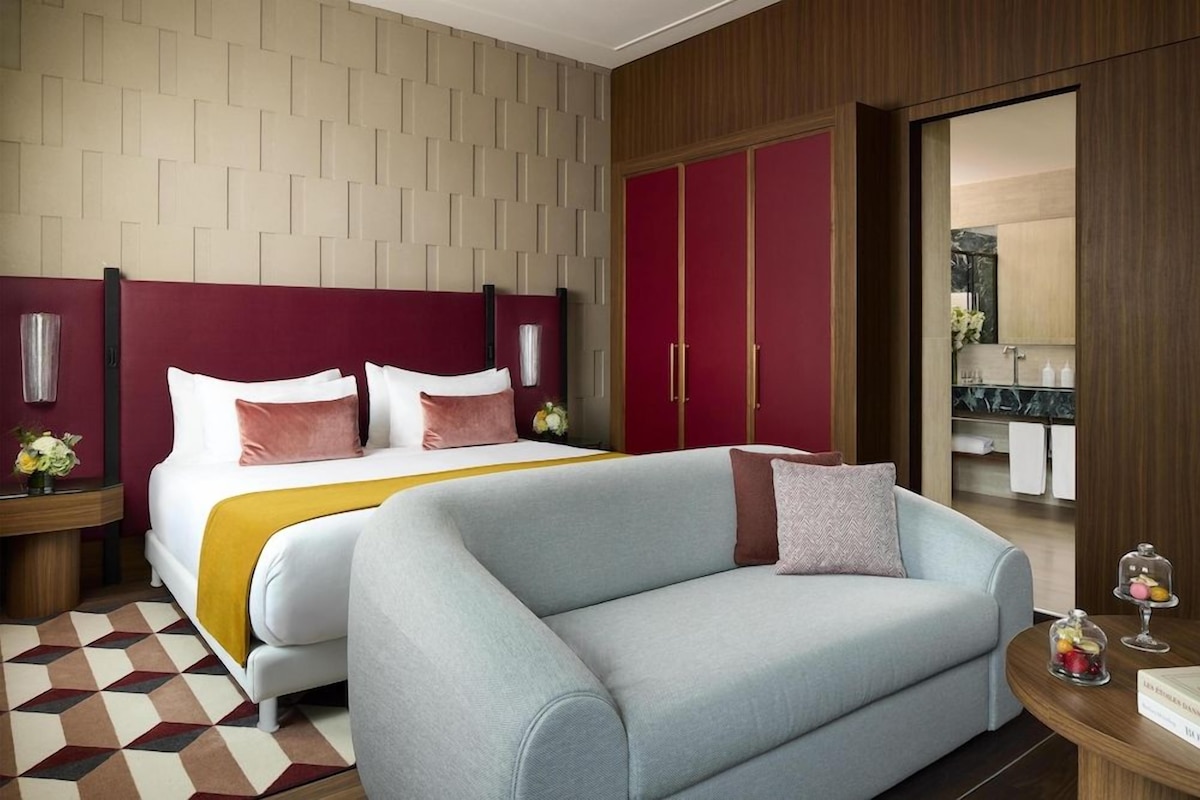 Een hotelkamer met een bed, een slaapbank, een kledingkast en een badkamer die door een open deur zichtbaar is.
