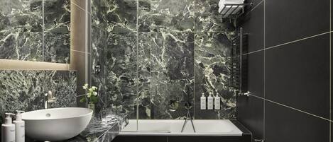 A modern bathroom with a large sink, a bathtub, and a toilet.