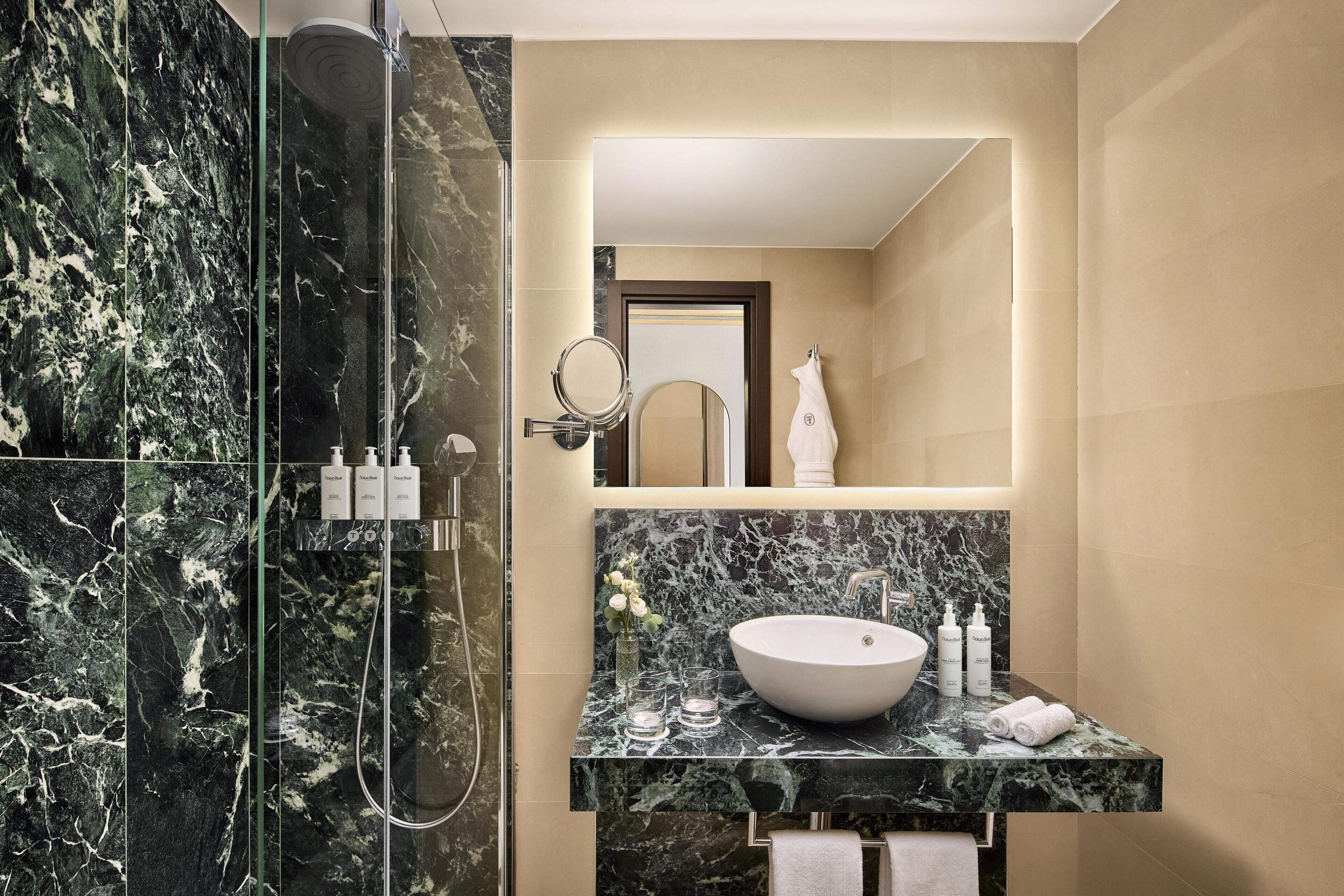 Une salle de bain moderne avec une douche à parois de verre, un meuble-lavabo en marbre et un grand miroir.