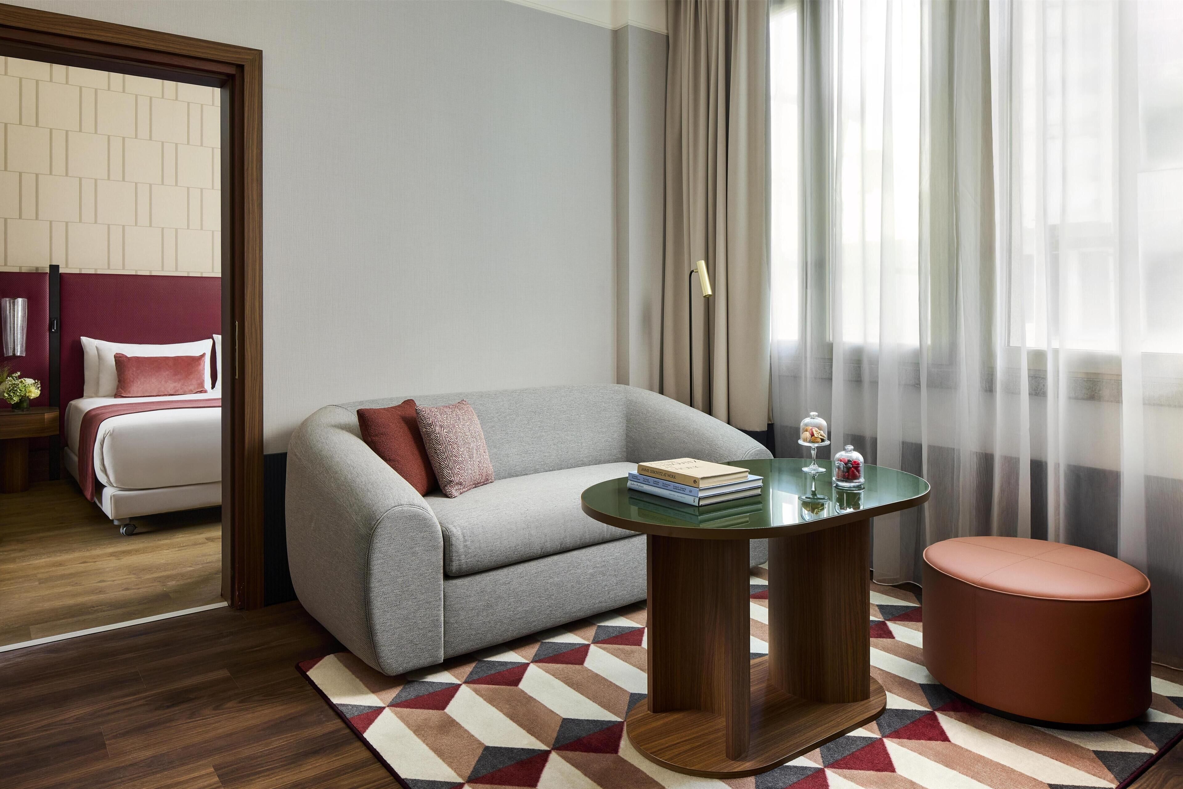 A modern room with a grey sofa, a round wooden table, and a patterned rug.