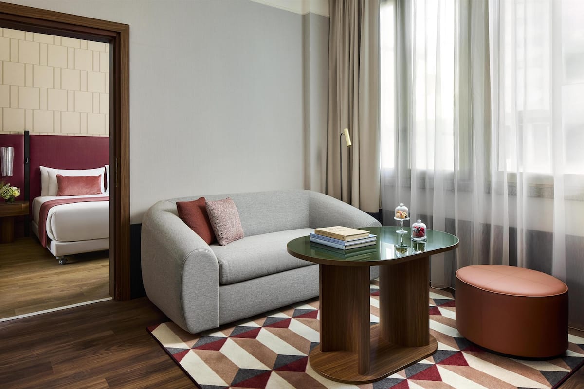 A modern room with a grey sofa, a round wooden table, and a patterned rug.