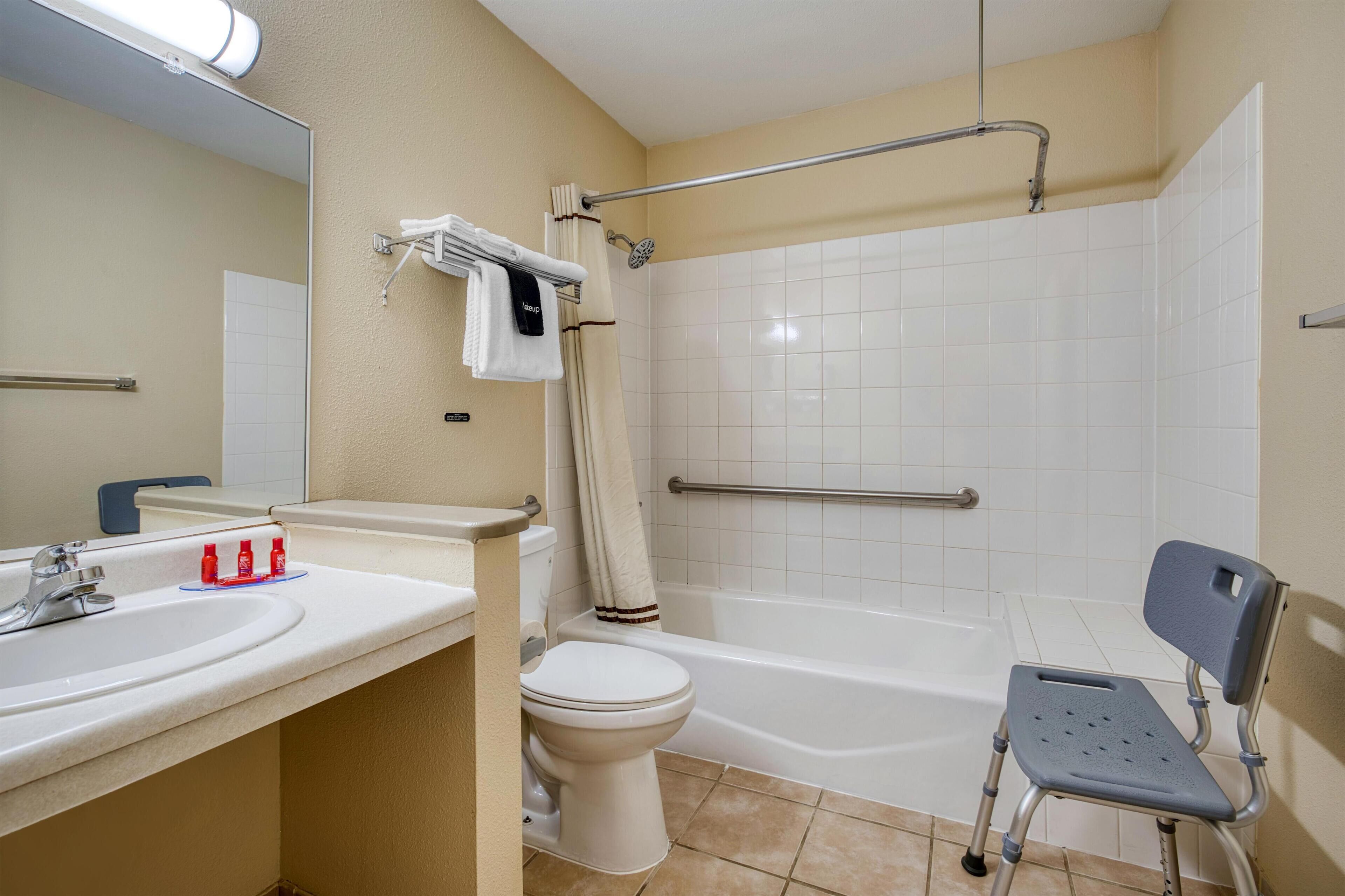 A bathroom with a sink, toilet, bathtub, and a shower with a grab bar.