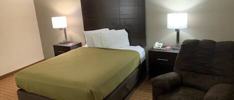 A hotel room with a bed, two bedside tables, a chair, and a lamp.