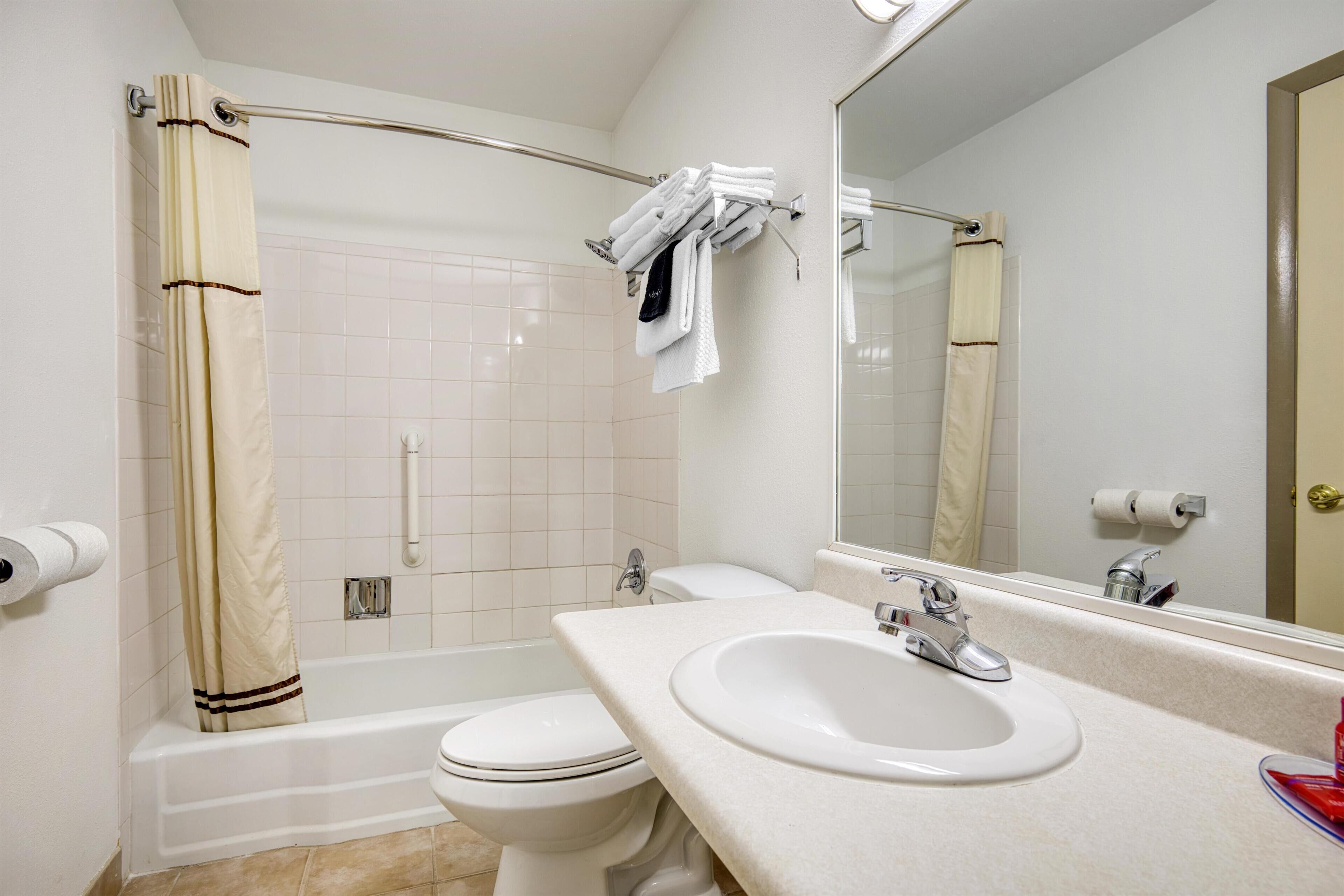 A bathroom with a bathtub, toilet, sink, and a shower curtain.