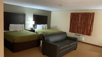 Una habitación de hotel con dos camas, un sofá, una mesita de noche con lámpara y una ventana con cortinas.