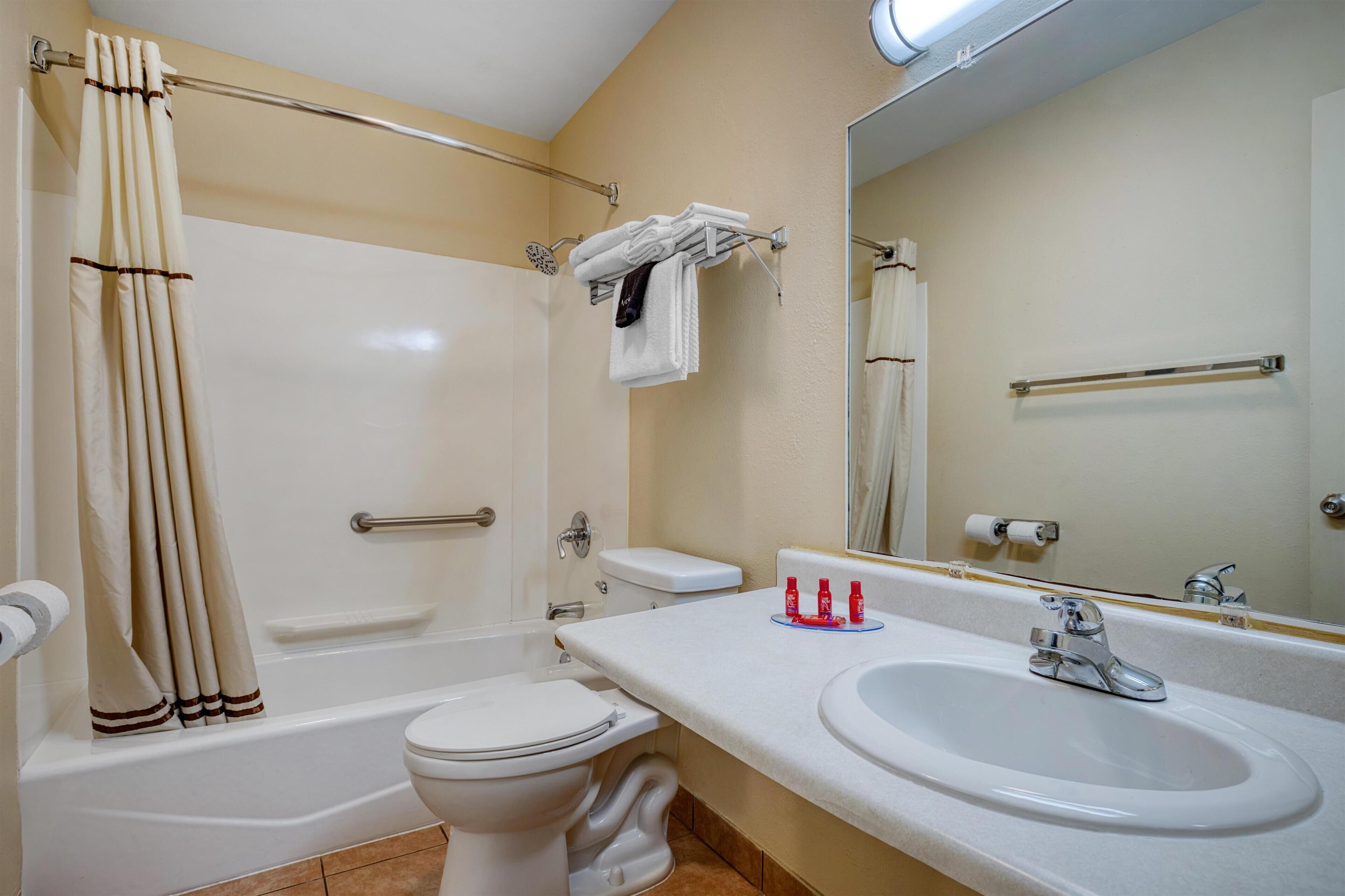 A bathroom with a bathtub, toilet, sink, and a mirror.