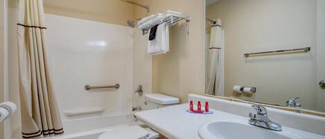 A bathroom with a bathtub, toilet, sink, and a mirror.