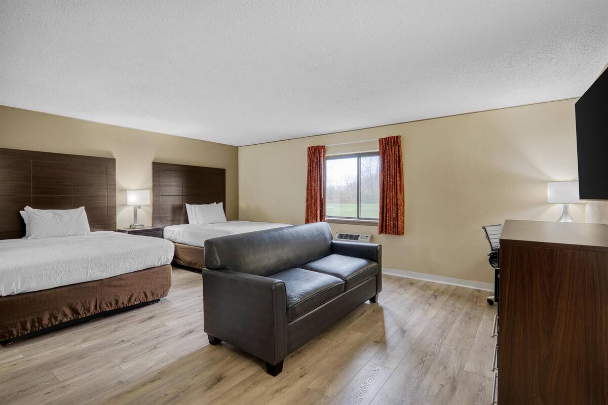 Een hotelkamer met een bed, een bank, een bureau en een raam met gordijnen.