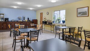 A dining area with multiple tables and chairs, a kitchen area with appliances, and a window with a view.