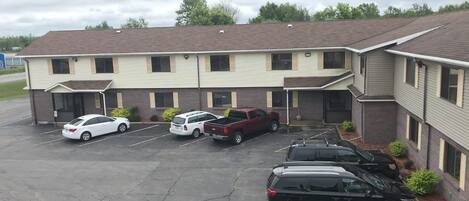 A motel with a parking lot containing several cars and a black SUV.