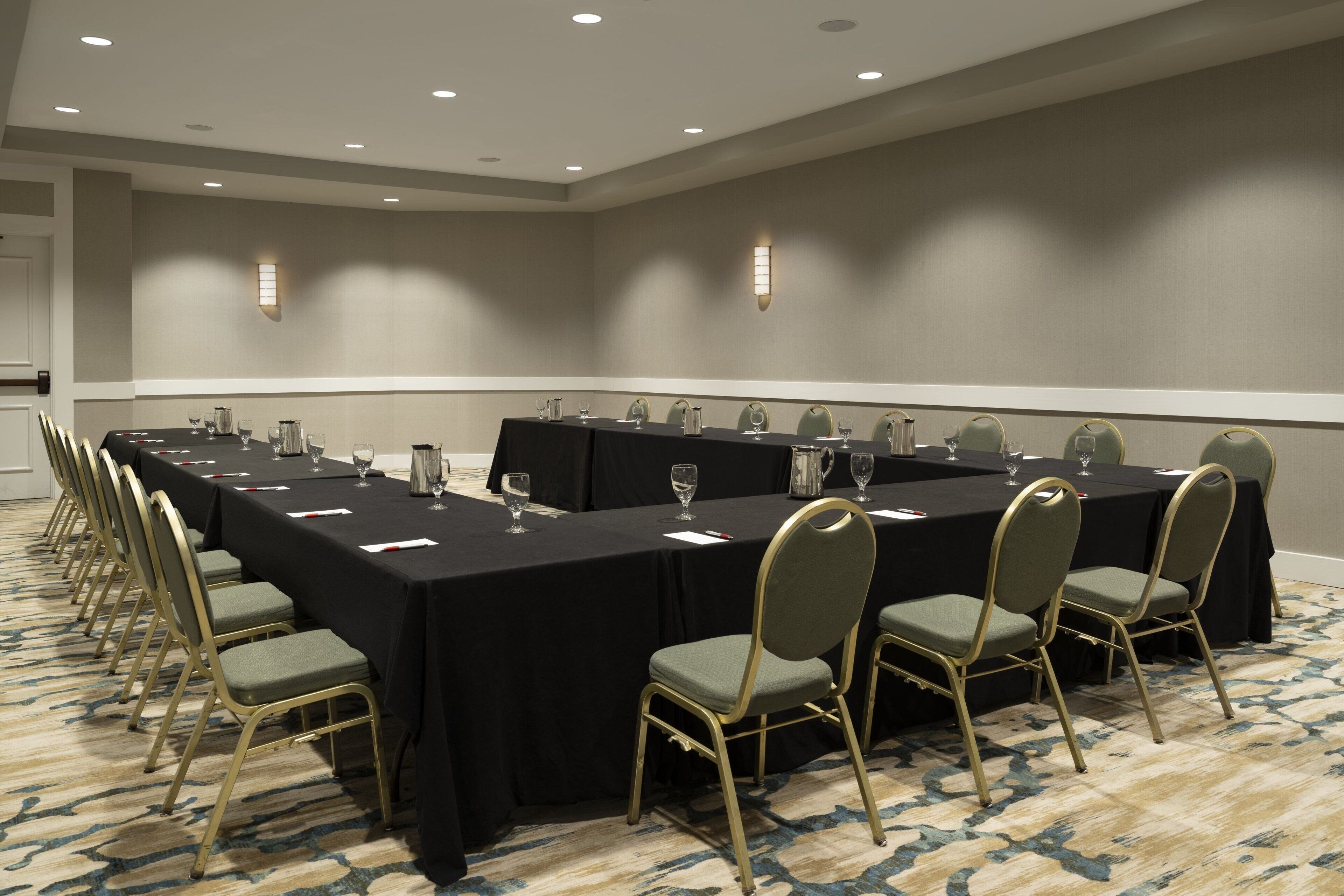 A conference room with a long table, chairs, and a carpeted floor.