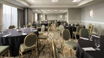 Una sala de conferencias con mesas redondas, sillas y suelo alfombrado.