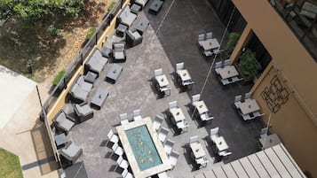 An outdoor patio area with multiple seating arrangements, including sofas and tables, and a central rectangular pool.