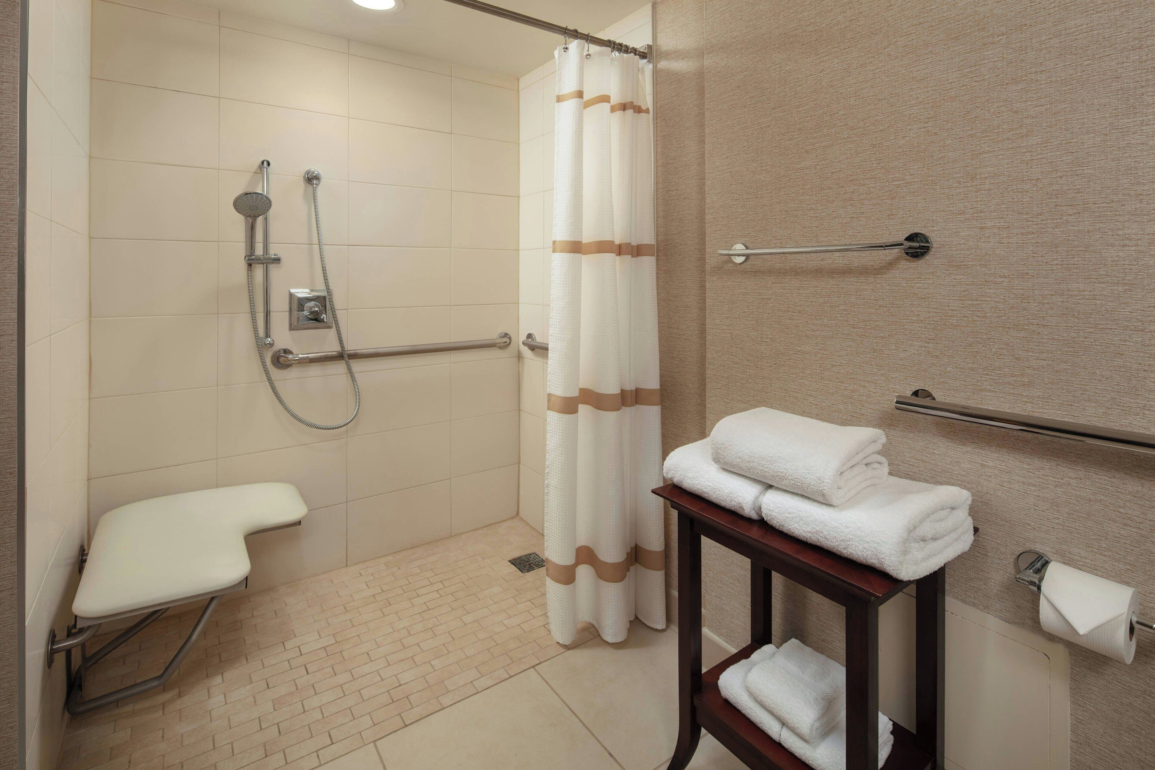 A bathroom with a shower, toilet, and a towel rack.
