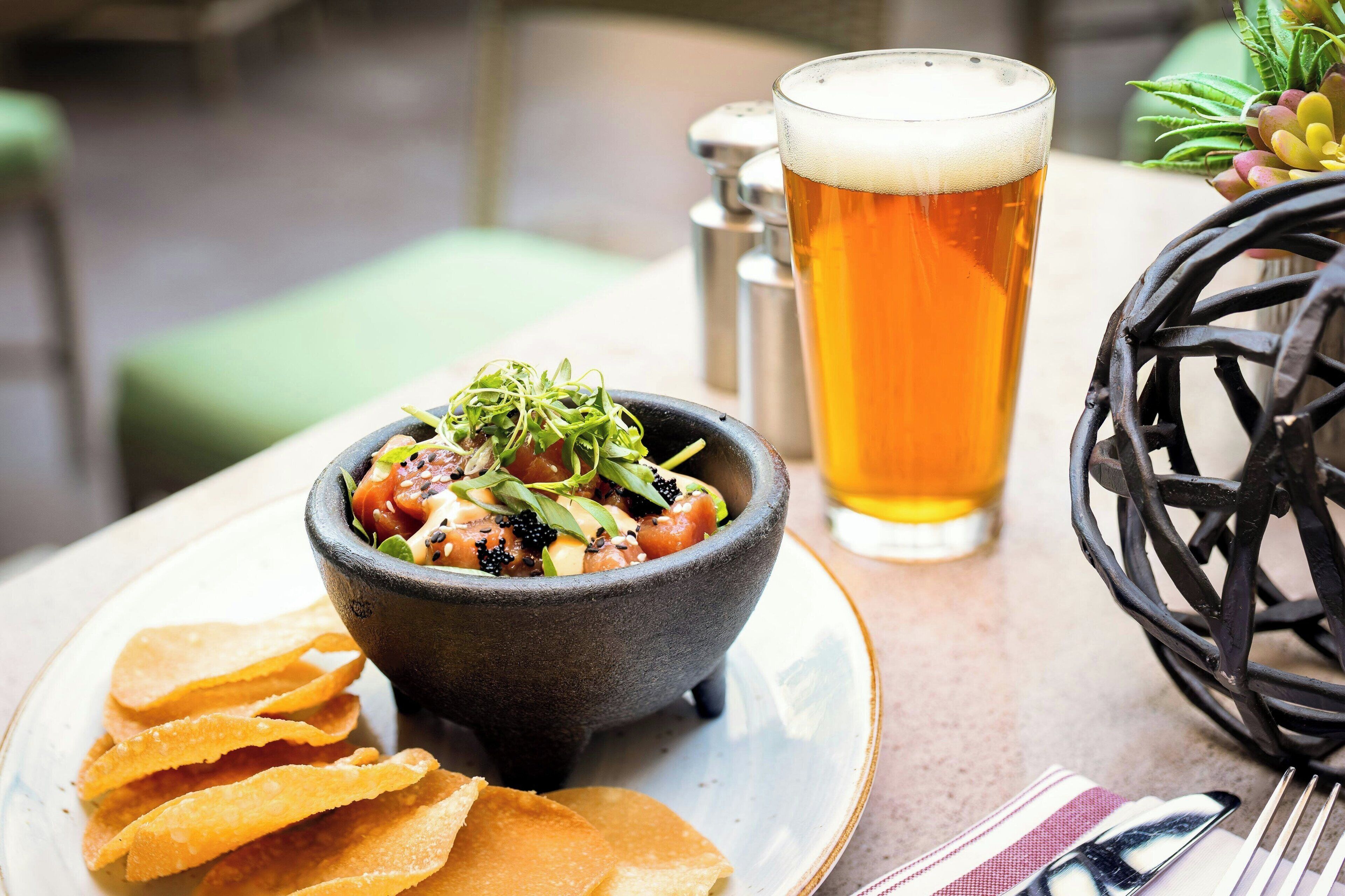 Un plato de comida con papas fritas y una cerveza en una mesa.