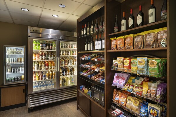 Una tienda de conveniencia con vitrinas refrigeradas para bebidas, pasillos con aperitivos y una selección de licores.