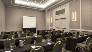 A conference room with tables, chairs, and a projector screen.