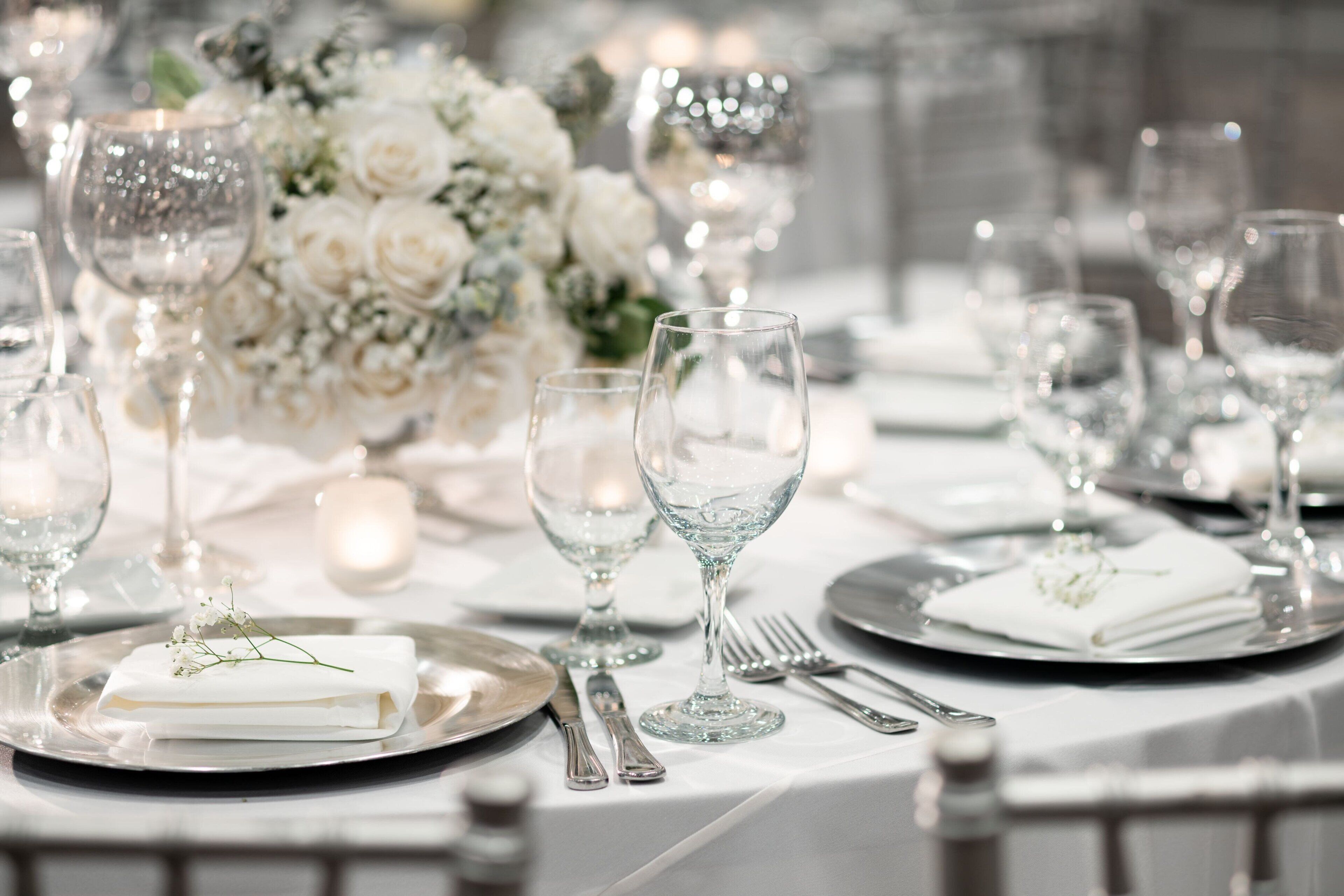 A table set for a formal event with clear glassware, folded napkins, and a floral centerpiece.