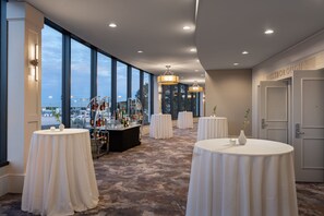 A hotel lobby with large windows, round tables, a bar area, and a door labeled "HILLSBOROUGH". - Tampa Airport Marriott (Tampa)