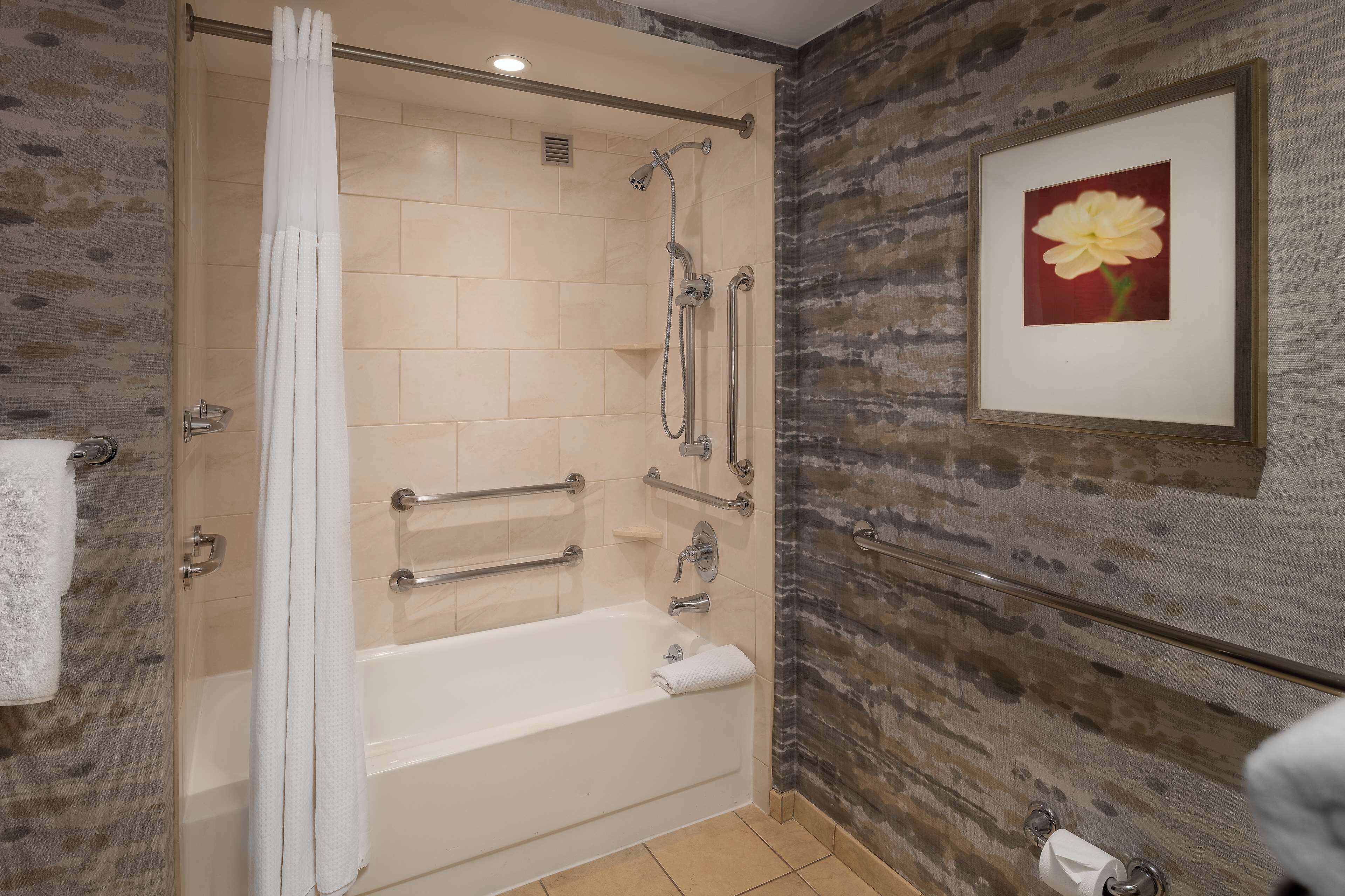 Un baño moderno con cabina de ducha, bañera y un cuadro con flores en la pared.