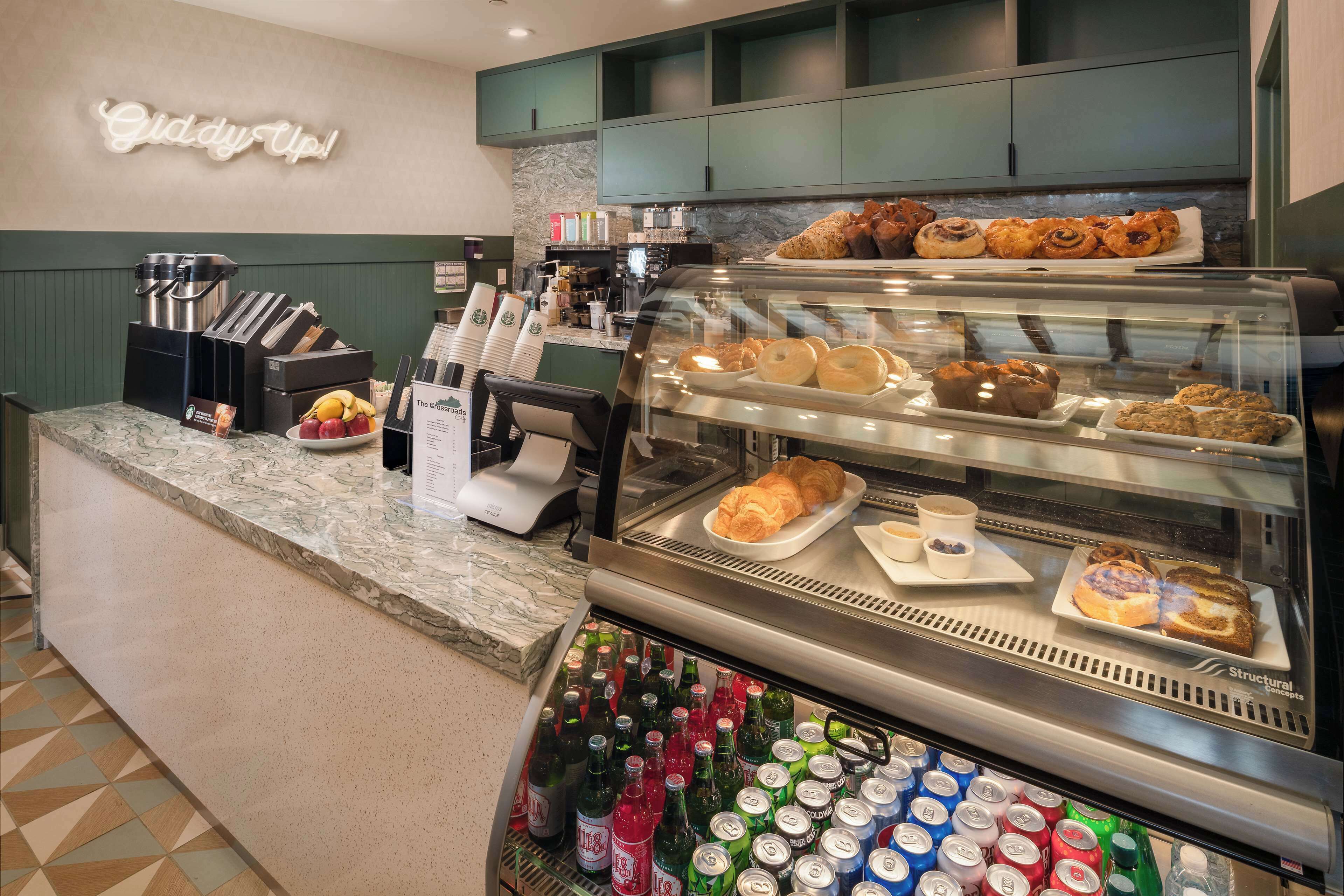 A bakery display case with pastries, a coffee machine, and a beverage cooler with various drinks.