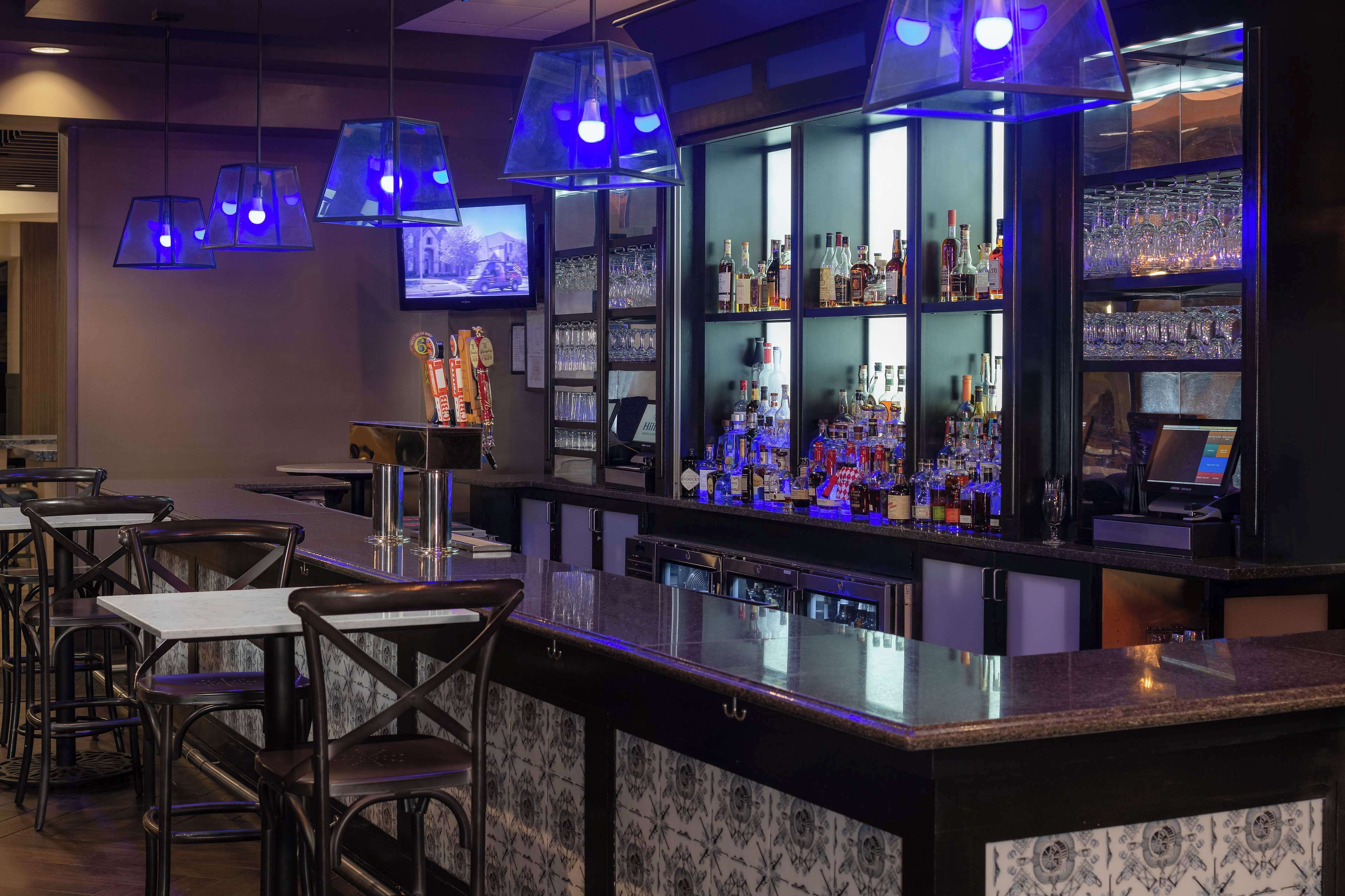 Eine Bar mit Marmorplatte, verschiedenen Sitzmöglichkeiten und einem an der Wand montierten Fernseher.