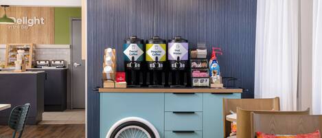A kitchenette with a coffee station featuring decaf, regular, and hot water options, a small fridge, and a wheelchair-accessible cart.