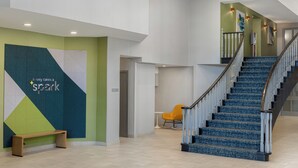 A modern interior with a staircase, a bench, and a wall with a motivational quote. - Spark by Hilton Toronto Mississauga (Mississauga)