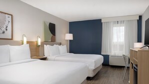 A hotel room with two beds, a desk, a chair, a lamp, and a window with curtains. - Spark by Hilton Toronto Mississauga (Mississauga)