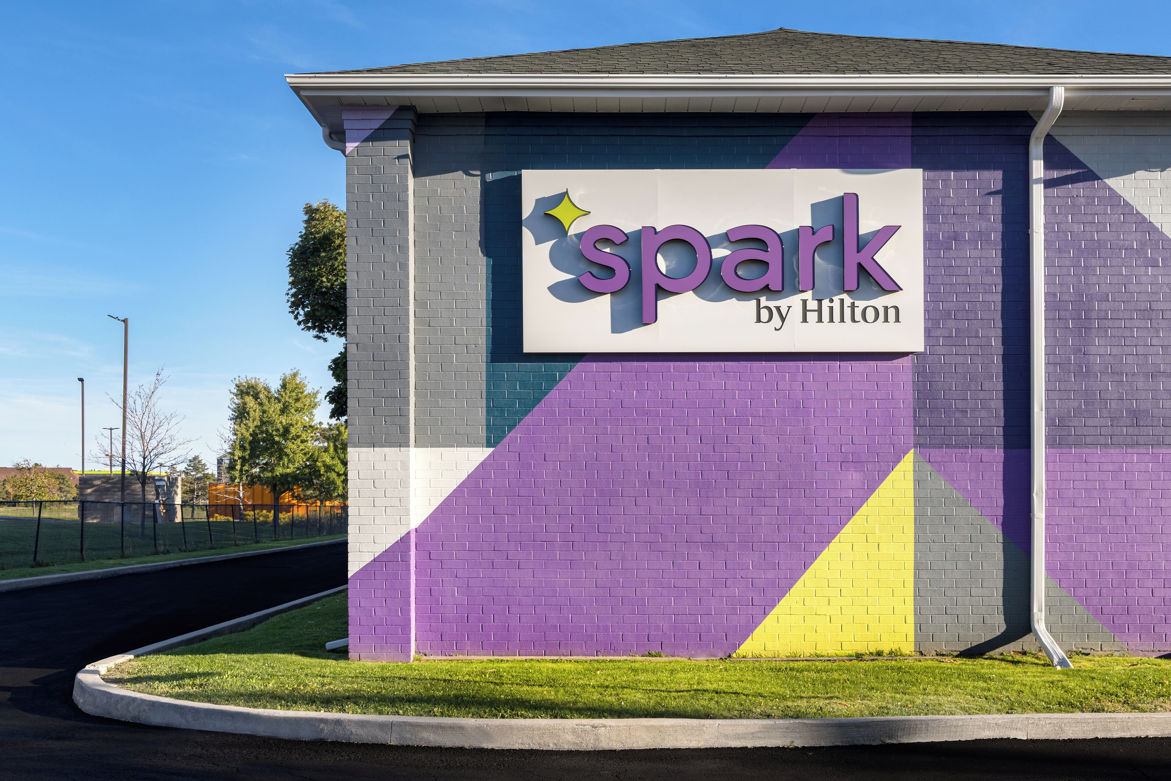 A building with a sign that reads "spark by Hilton" on a purple and gray brick wall.